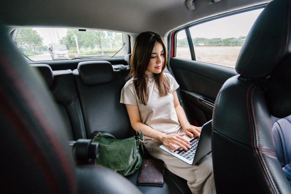 Woman using a laptop at the back of the car