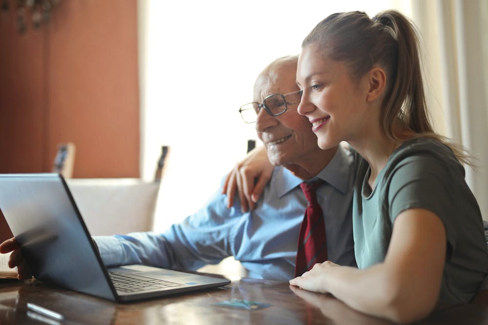 Young woman and an elderly man using a laptop